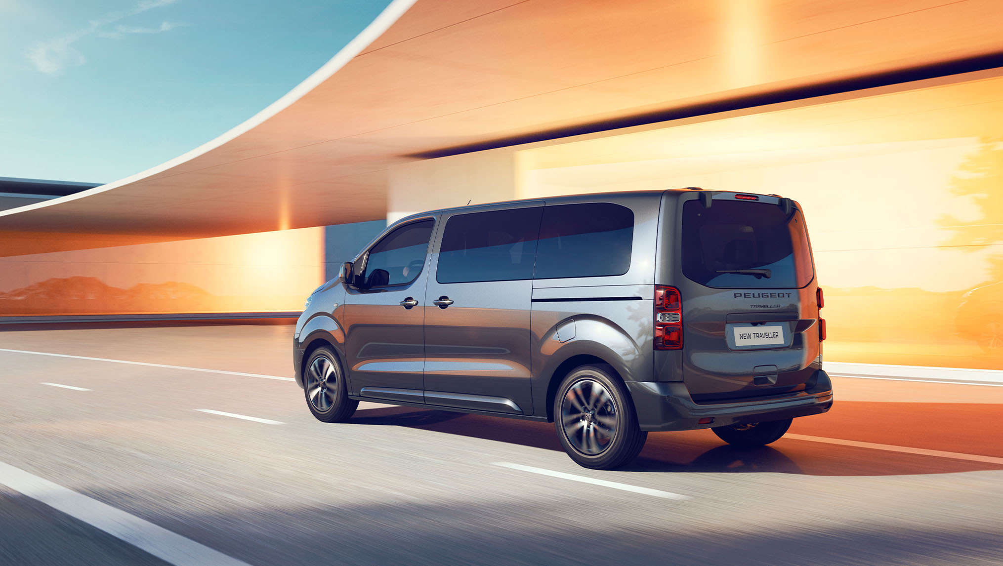 Peugeot Traveller їде по дорозі, вигляд ззаду з лівого боку